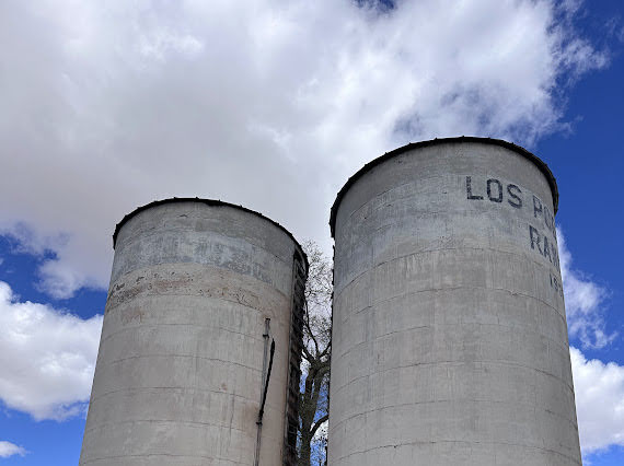 Two grain bins with Los Poblanos on the side of one