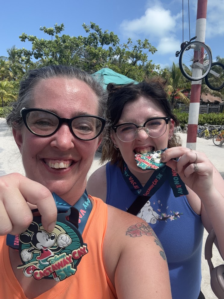 A picture of two females holding up Castaway Cay 5K medals