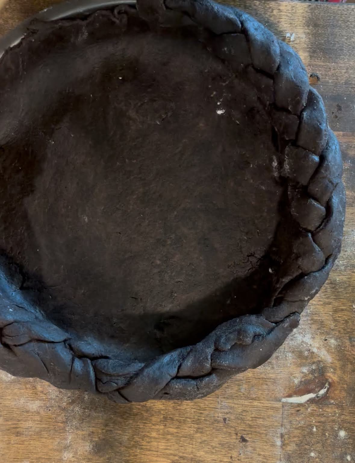 A chocolate pie crust with braided edges on a wooden table