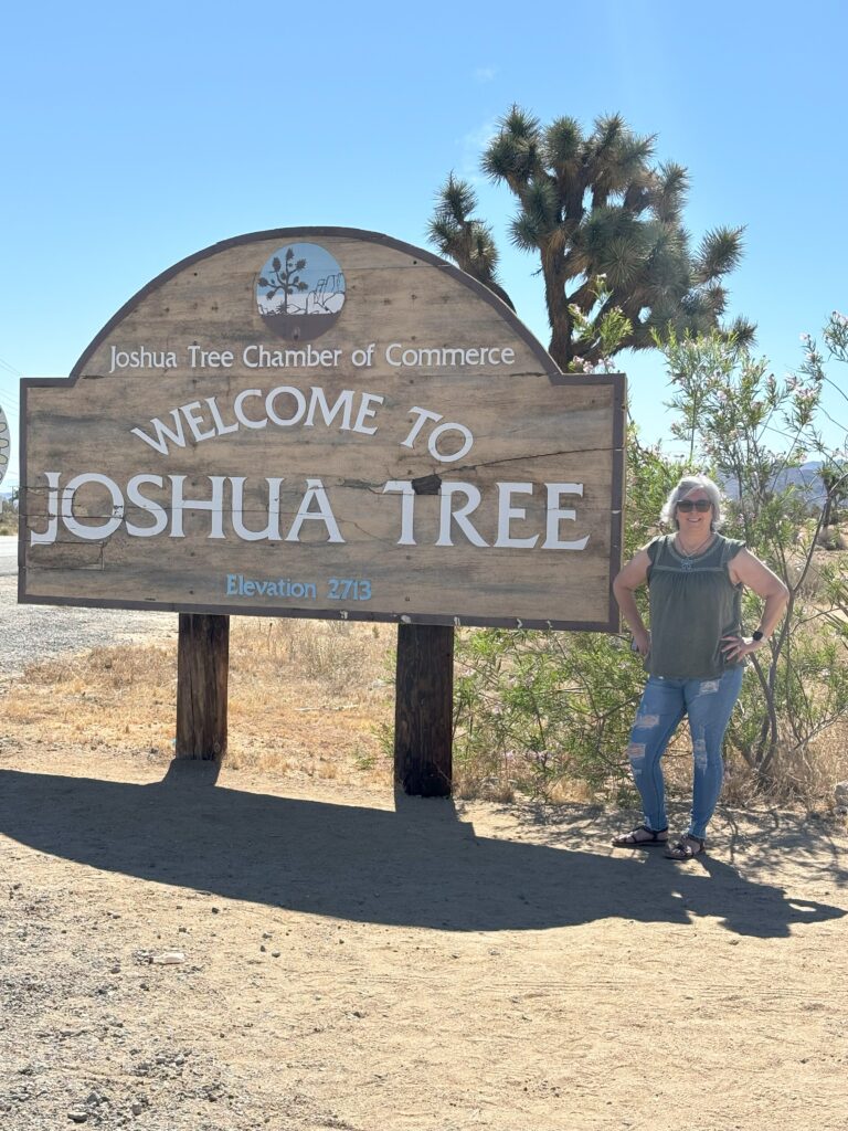 A woman standing next to a Joshua Tree sign